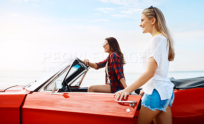 Buy stock photo Shot of a two happy young women enjoying a summer’s road trip together