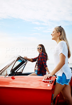 Buy stock photo Shot of a two happy young women enjoying a summer’s road trip together