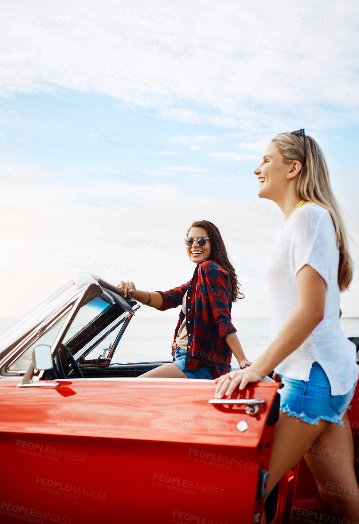 Buy stock photo Shot of a two happy young women enjoying a summer’s road trip together