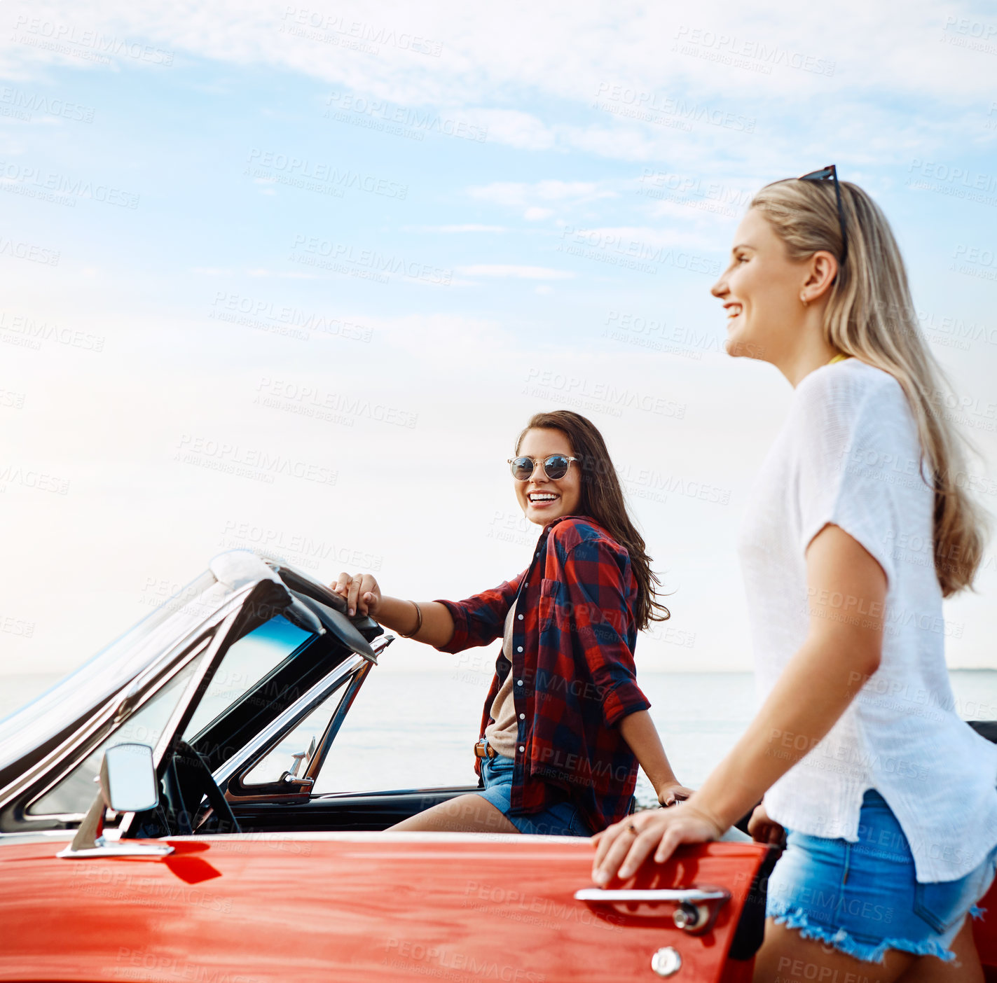 Buy stock photo Shot of a two happy young women enjoying a summer’s road trip together