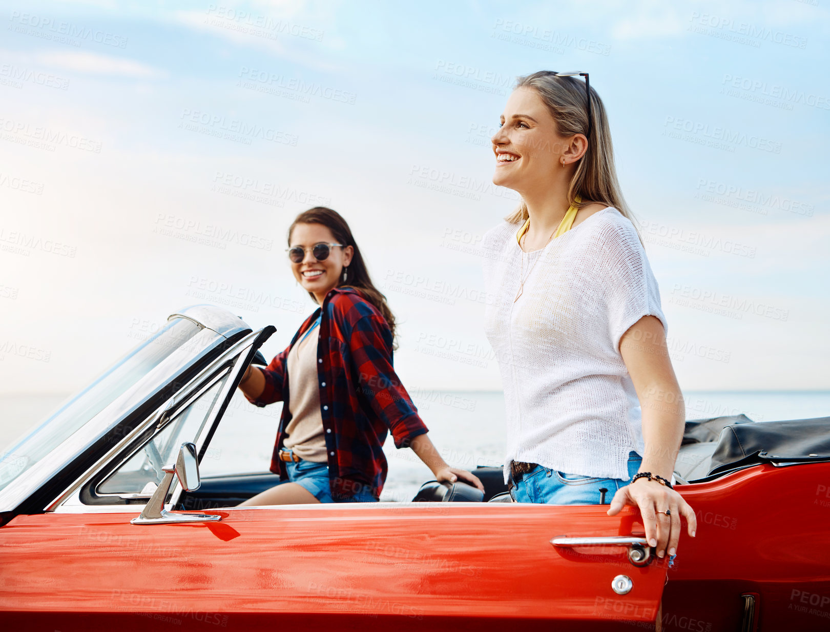 Buy stock photo Shot of a two happy young women enjoying a summer’s road trip together