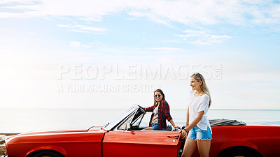 Buy stock photo Shot of a two happy young women enjoying a summer’s road trip together