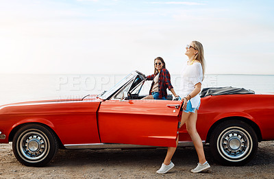 Buy stock photo Shot of a two happy young women enjoying a summer’s road trip together