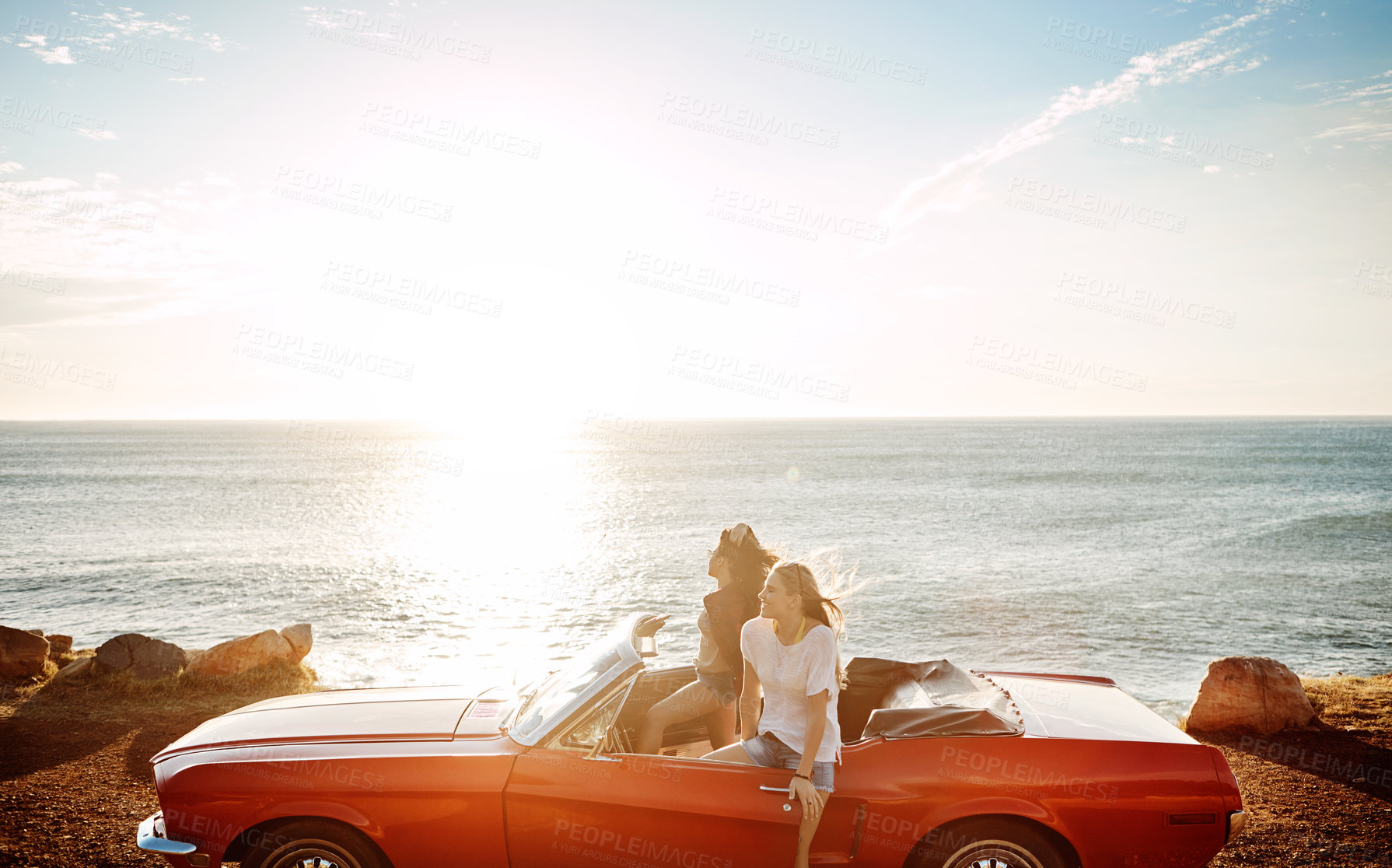 Buy stock photo Shot of a two happy young women enjoying a summer’s road trip together