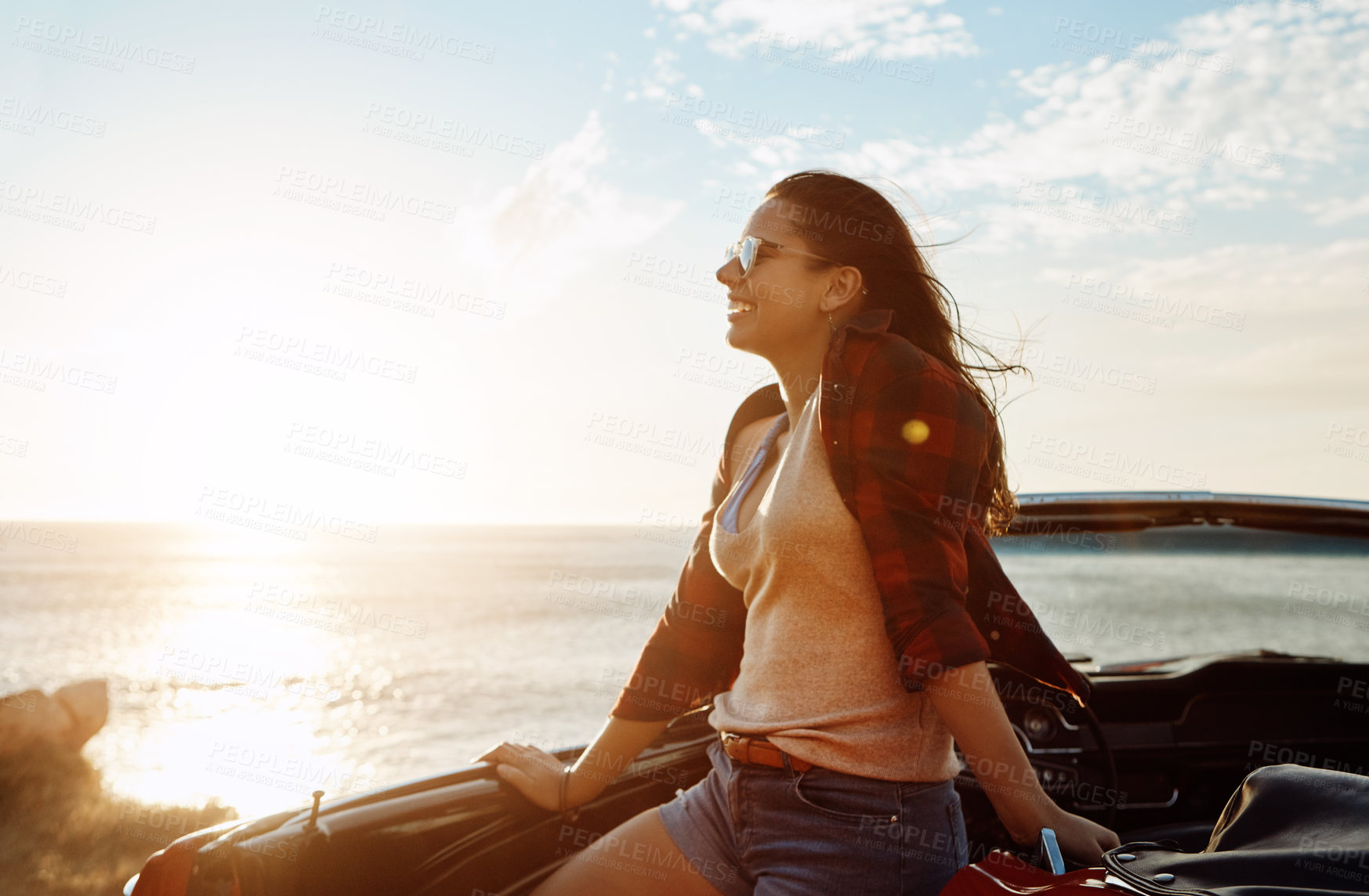 Buy stock photo Shot of a happy young woman enjoying a summer’s road trip