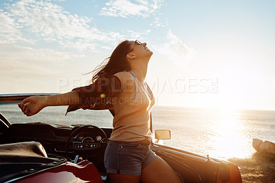 Buy stock photo Shot of a happy young woman enjoying a summer’s road trip