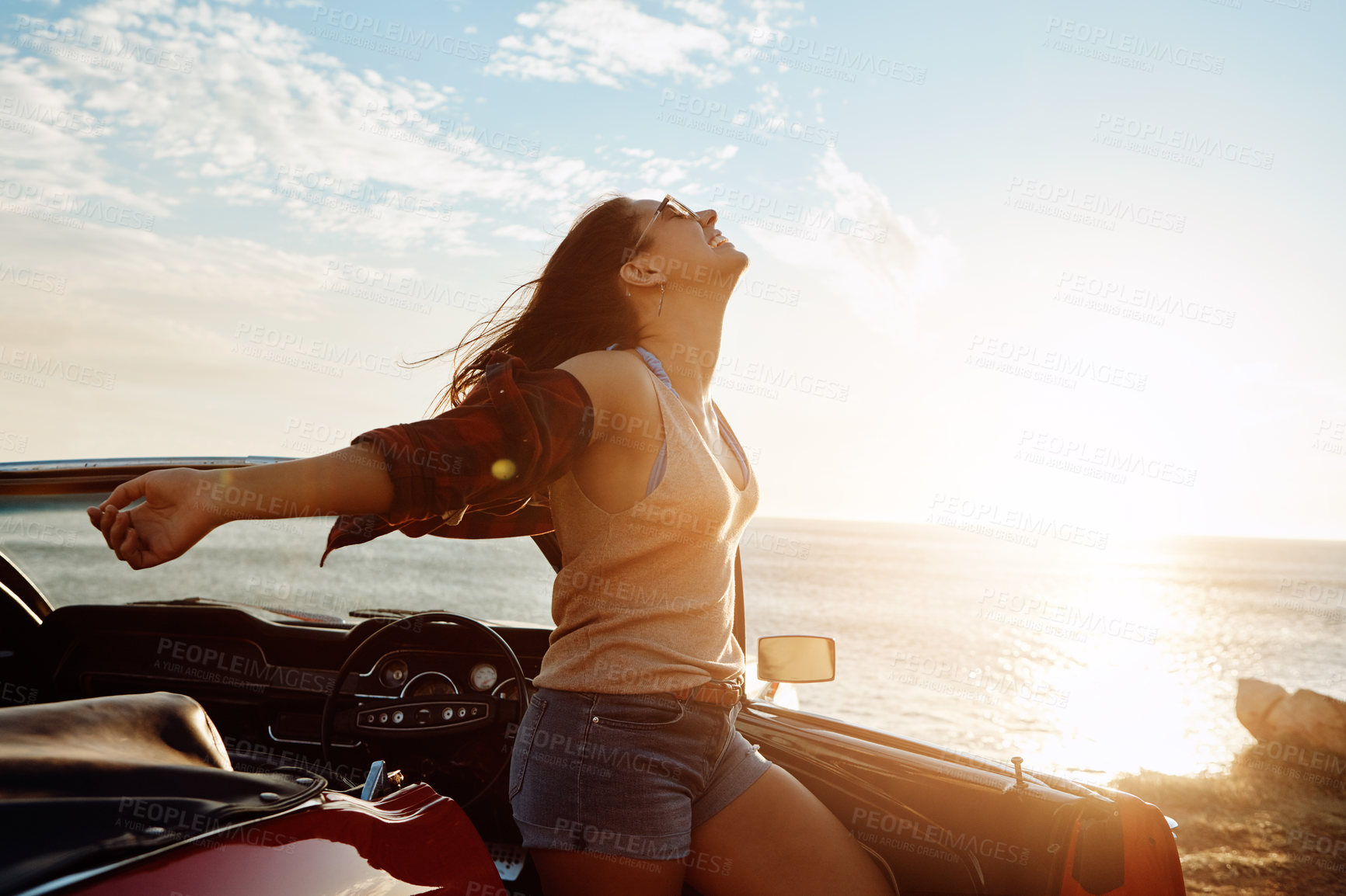 Buy stock photo Shot of a happy young woman enjoying a summer’s road trip