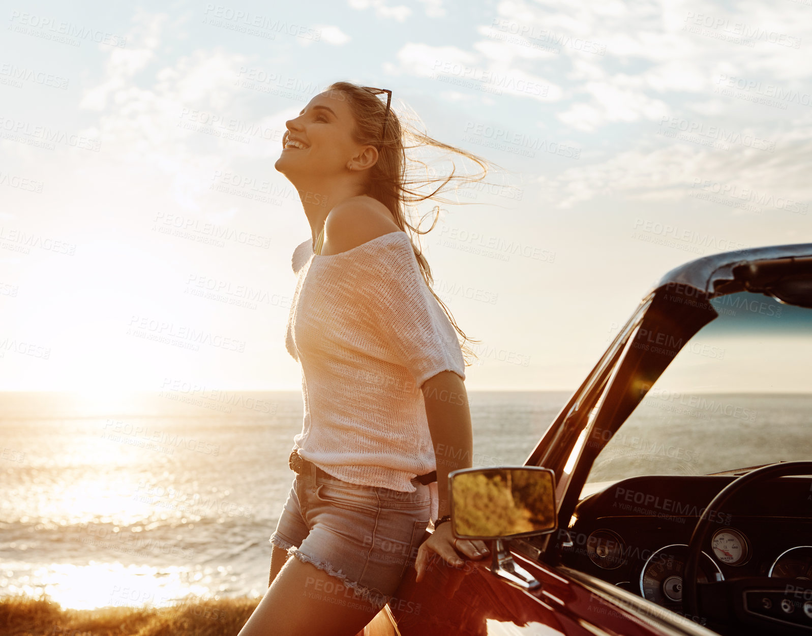 Buy stock photo Shot of a happy young woman enjoying a summer’s road trip