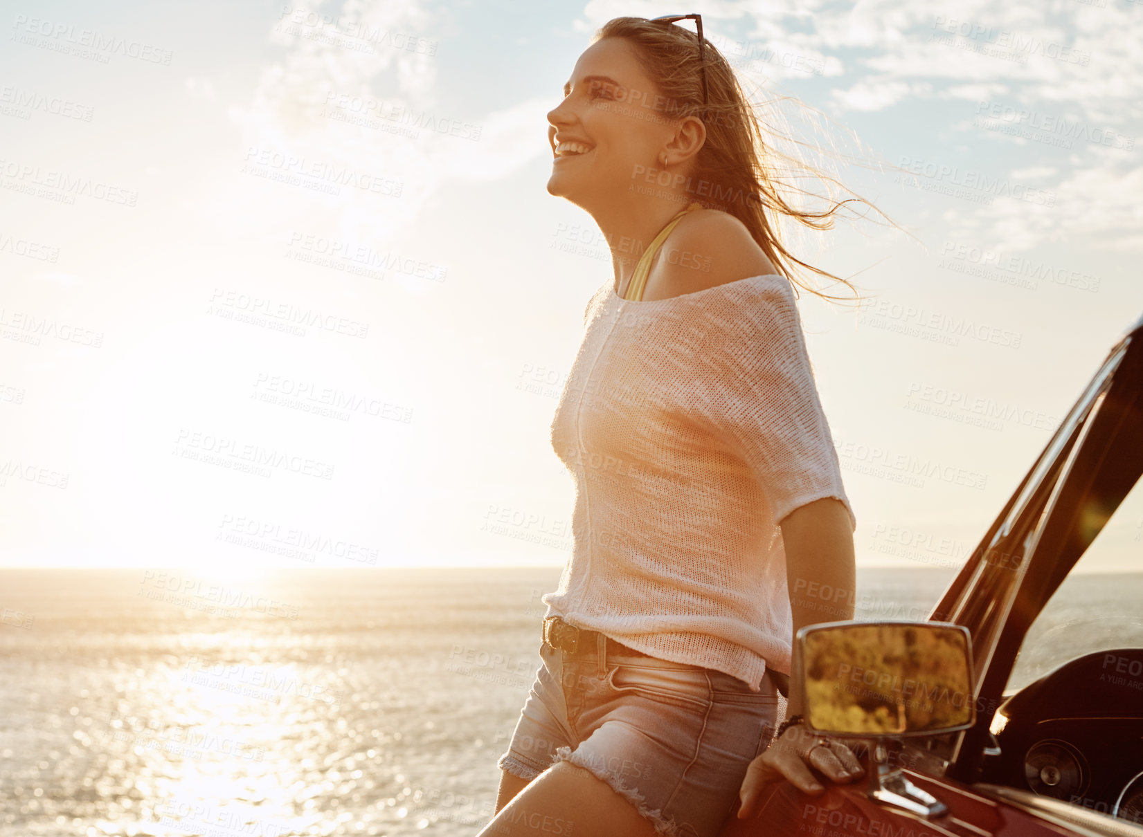 Buy stock photo Shot of a happy young woman enjoying a summer’s road trip