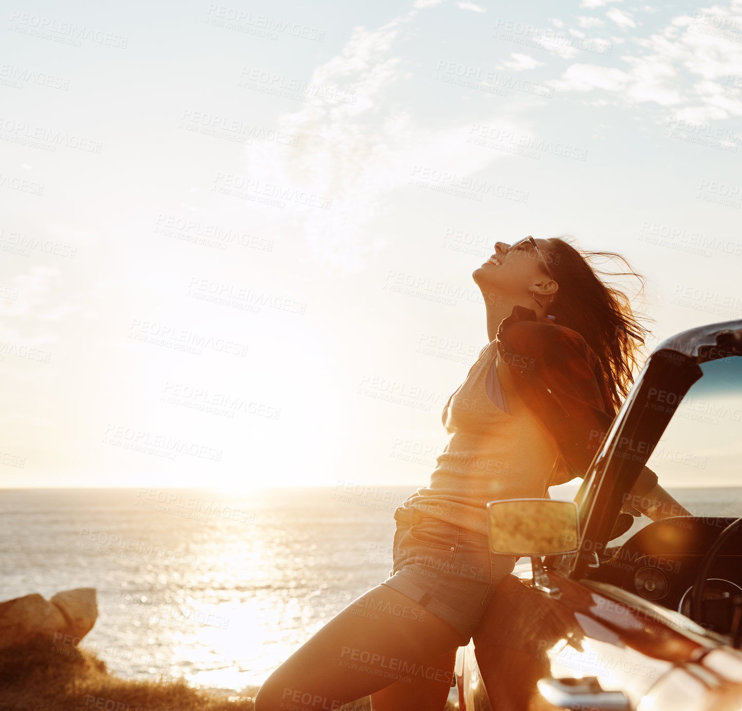 Buy stock photo Shot of a happy young woman enjoying a summer’s road trip