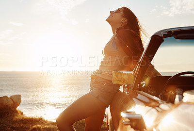 Buy stock photo Shot of a happy young woman enjoying a summer’s road trip