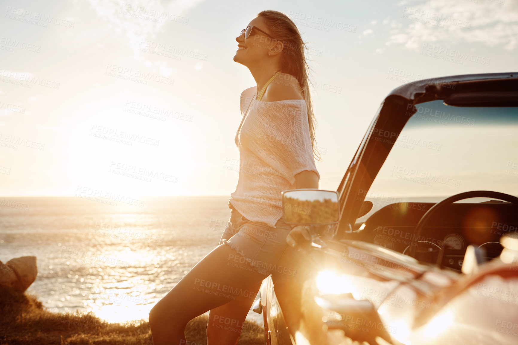 Buy stock photo Shot of a happy young woman enjoying a summer’s road trip