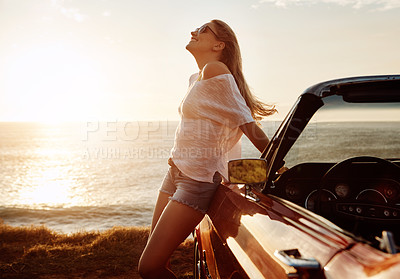 Buy stock photo Shot of a happy young woman enjoying a summer’s road trip