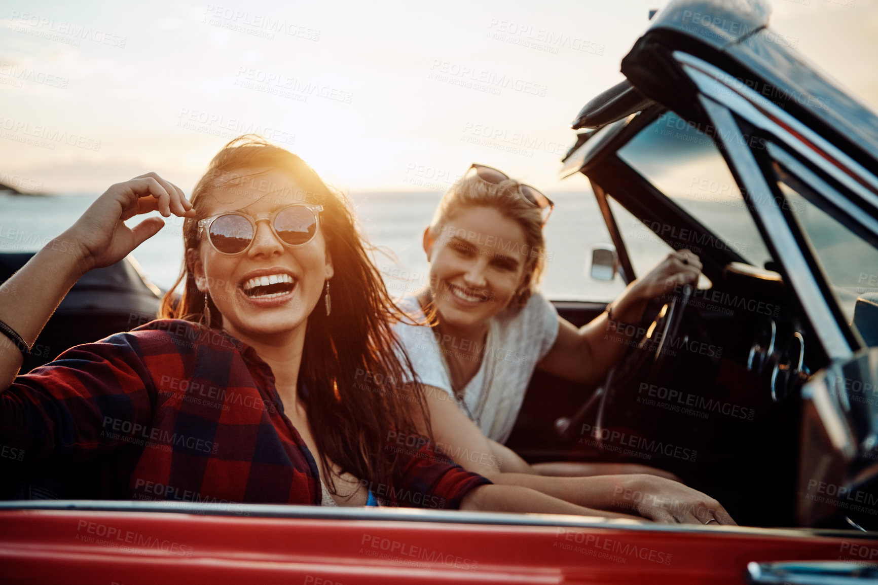 Buy stock photo Shot of a two happy young women enjoying a summer’s road trip together