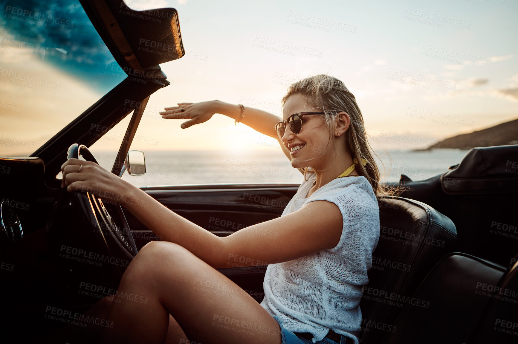 Buy stock photo Shot of a happy young woman enjoying a summer’s road trip