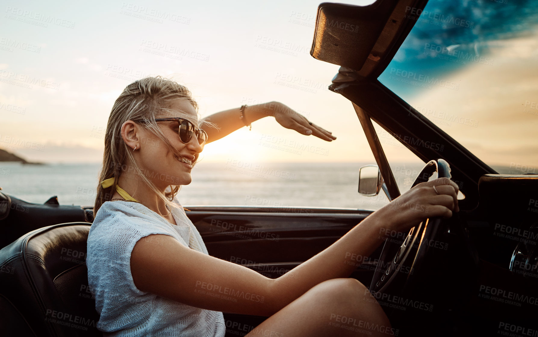 Buy stock photo Shot of a happy young woman enjoying a summer’s road trip