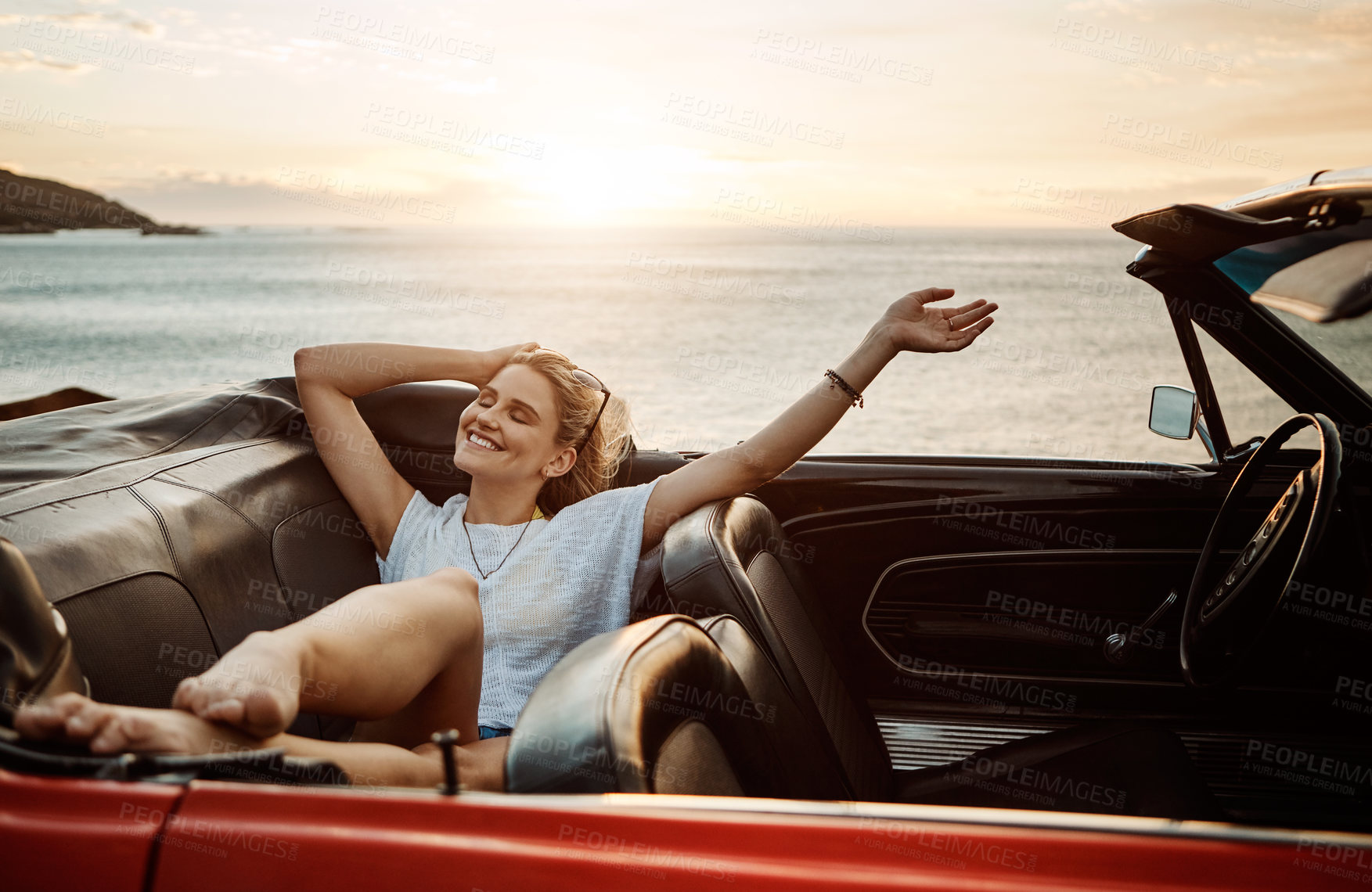 Buy stock photo Shot of a happy young woman enjoying a summer’s road trip