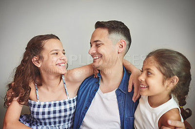 Buy stock photo Happy, man and hug daughters with love at house for fathers day, bonding together and support. Smile, parent and children with hug for family, care and laughing for funny joke on studio background