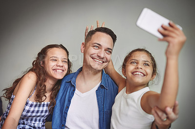 Buy stock photo Shot of a young girl taking a selfie with her father and sister