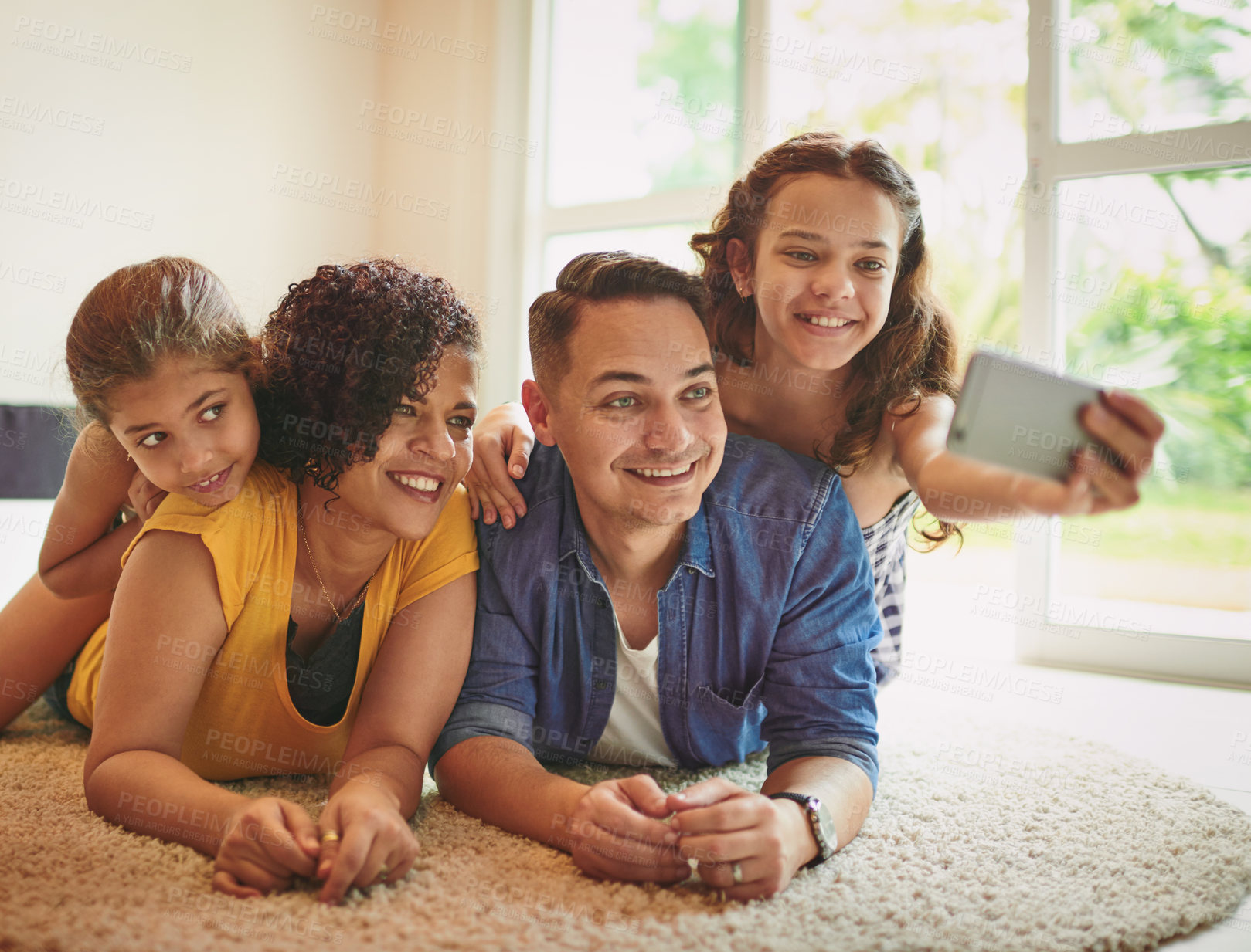 Buy stock photo Shot of a happy family of four taking a selfie together at home