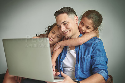 Buy stock photo Shot of a man and his two daughters looking at something on a laptop