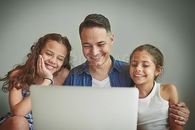 Buy stock photo Shot of a man and his two daughters looking at something on a laptop