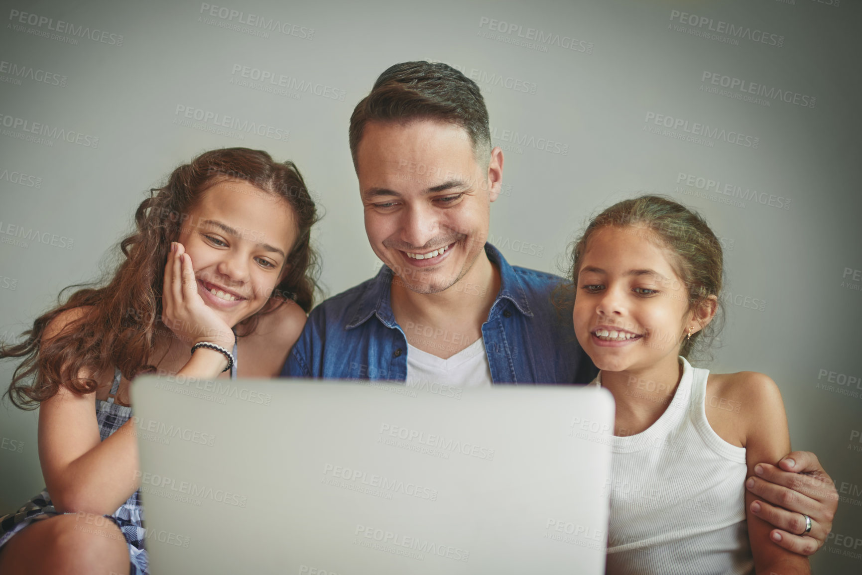 Buy stock photo Shot of a man and his two daughters looking at something on a laptop