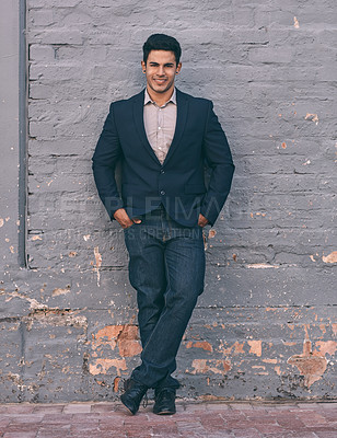 Buy stock photo Portrait of a handsome young businessman standing against a face brick wall with his hands in pockets