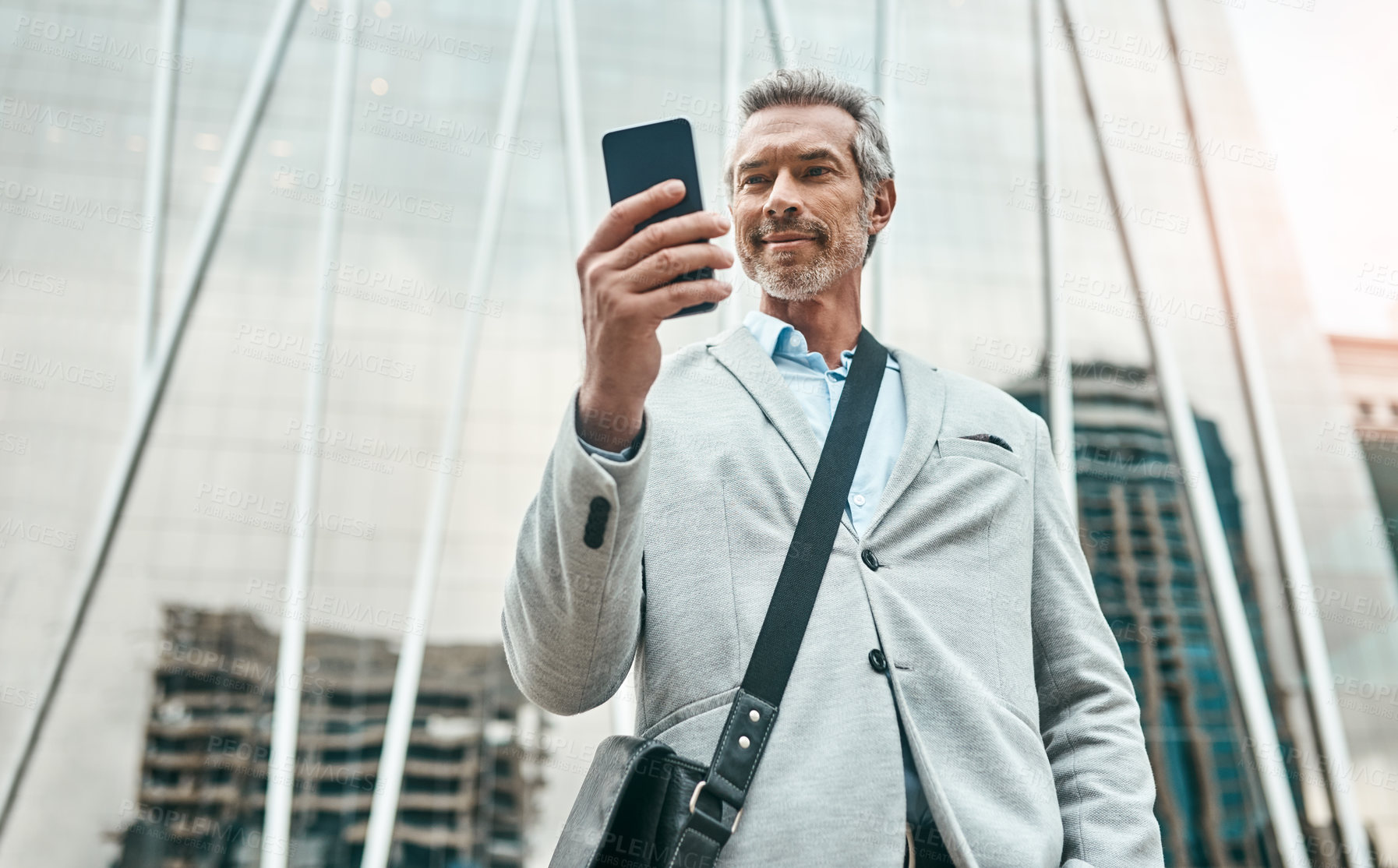 Buy stock photo Shot of a mature businessman using a cellphone in the city