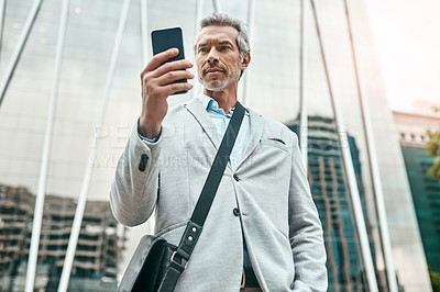 Buy stock photo Shot of a mature businessman using a cellphone in the city