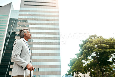 Buy stock photo Shot of a mature businessman walking with a suitcase in the city
