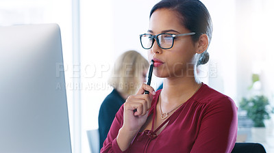 Buy stock photo Cropped shot of a focused young businesswoman working on her computer while contemplating inside of the office