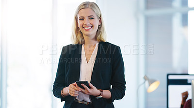 Buy stock photo Portrait of a confident young businesswoman holding her cellphone while standing inside of the office