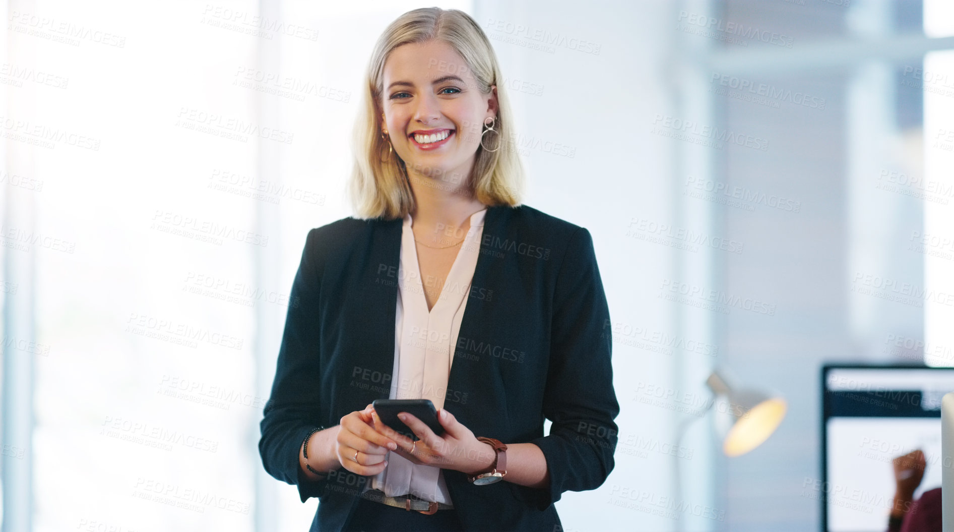 Buy stock photo Portrait of a confident young businesswoman holding her cellphone while standing inside of the office