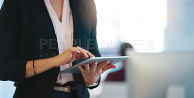 Buy stock photo Cropped shot of an unrecognizable businesswoman browsing on her digital tablet inside of the office during the day