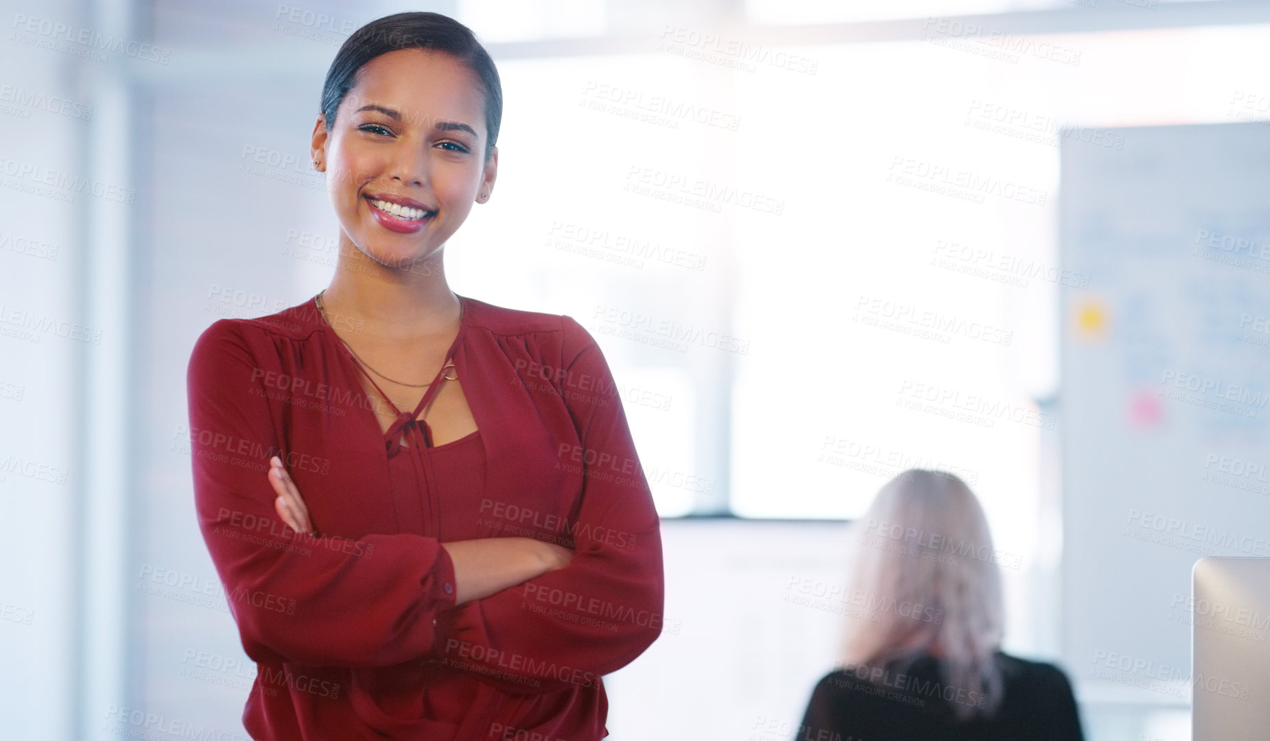 Buy stock photo Portrait of a confident young businesswoman standing with her arms folded inside of the office