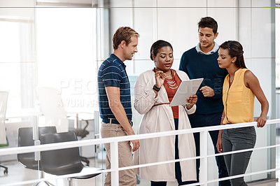 Buy stock photo Cropped shot of a diverse group of business people at work discussing ideas on a tablet in the office