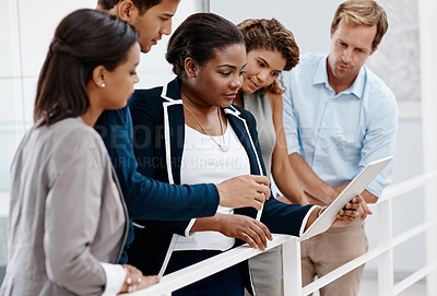 Buy stock photo Cropped shot of a diverse group of colleagues standing together and looking at a tablet in the office
