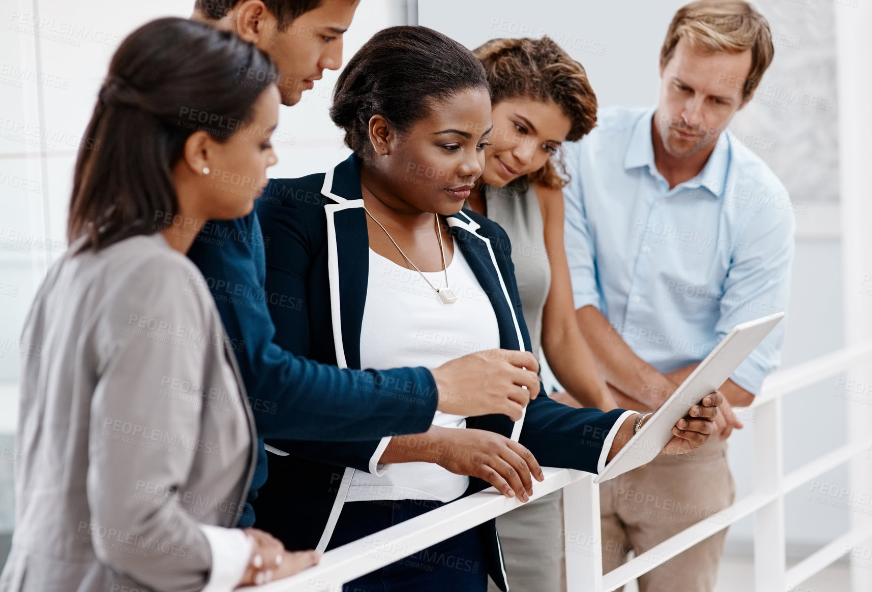Buy stock photo Cropped shot of a diverse group of colleagues standing together and looking at a tablet in the office