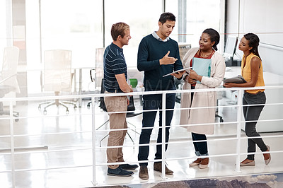 Buy stock photo Full length shot of a diverse group of colleagues at work discussing ideas on a tablet in the office