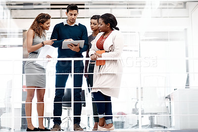 Buy stock photo Full length shot of a diverse young group of colleagues at work discussing ideas on a tablet in the office