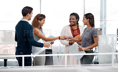 Buy stock photo Shot of a diverse young group of colleagues shaking hands in agreement at the office