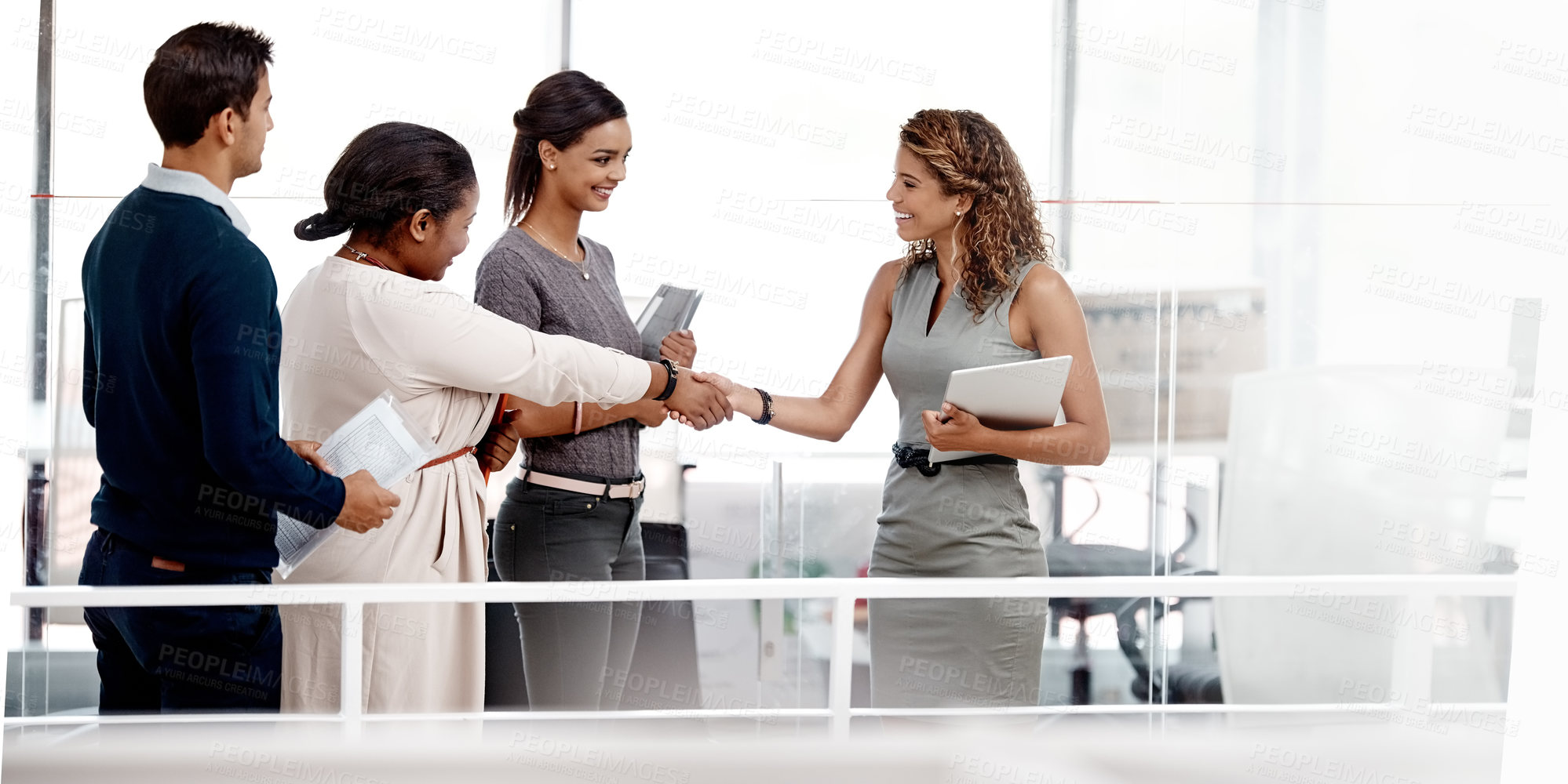 Buy stock photo Shot of a young diverse group of colleagues shaking hands in agreement at the office