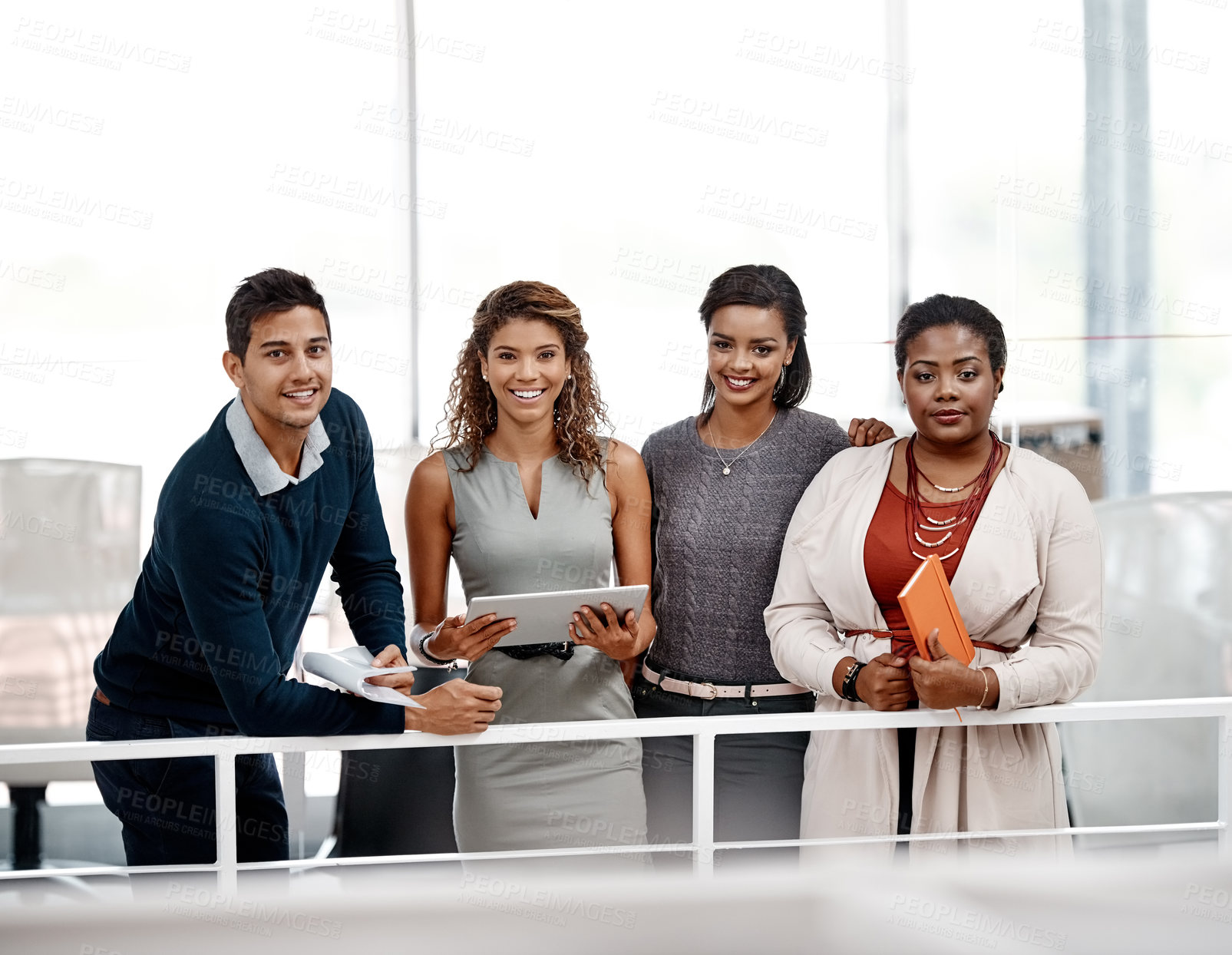 Buy stock photo Shot of a diverse young group of colleagues standing together in the office and smiling at the camera