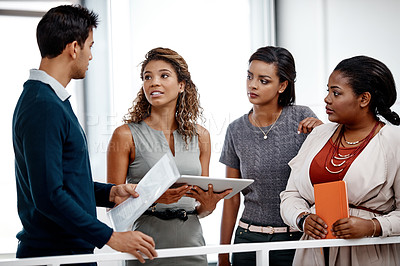 Buy stock photo Shot of a diverse young group of colleagues at work discussing ideas on a tablet in the office