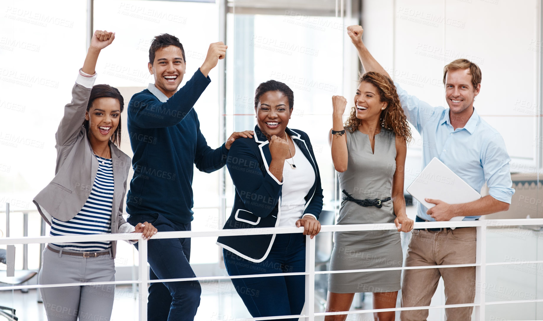 Buy stock photo Shot of a diverse group of colleagues celebrating success with their arm raised at the office