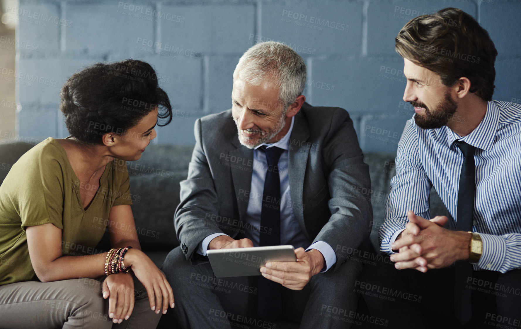 Buy stock photo Cropped shot of three businesspeople working together on a digital tablet in their office