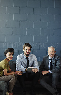 Buy stock photo Cropped portrait of three businesspeople working together on a digital tablet in their office