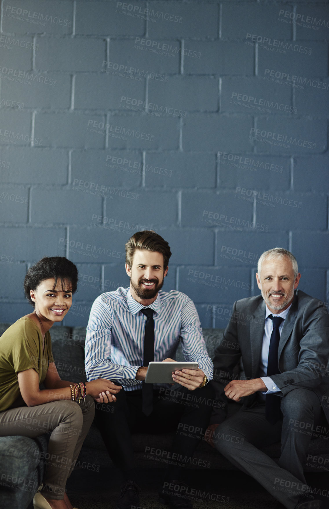 Buy stock photo Cropped portrait of three businesspeople working together on a digital tablet in their office