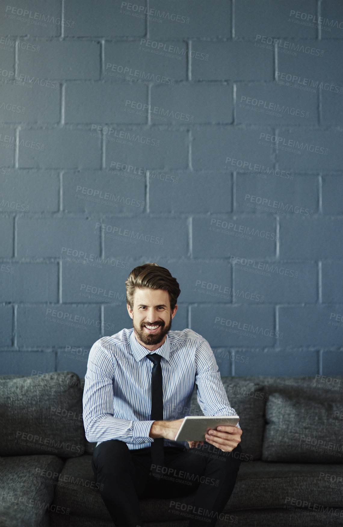 Buy stock photo Cropped portrait of a handsome young businessman using his digital tablet in the office